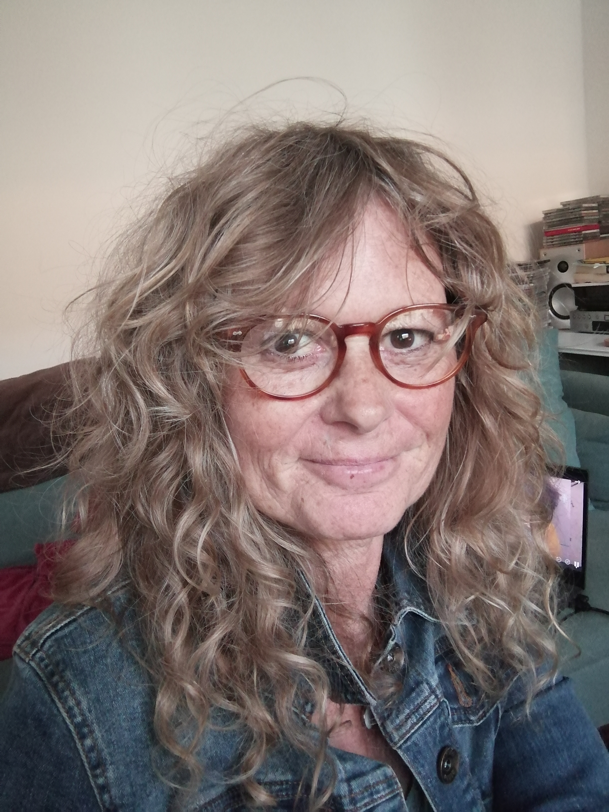 white woman with curly hair and glasses smiling for the camera