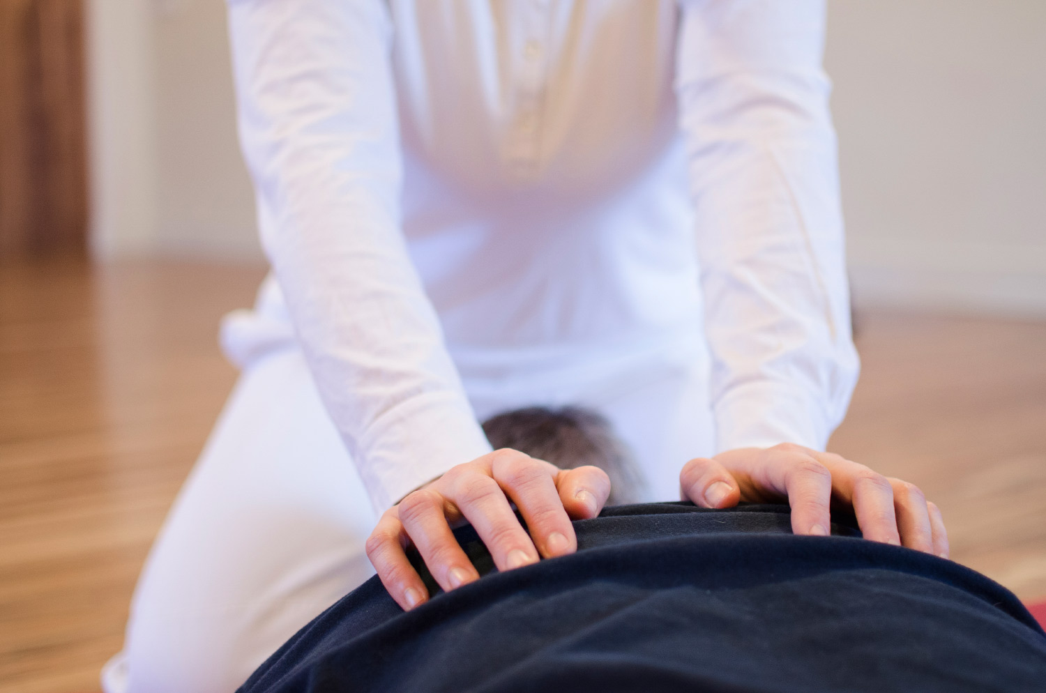 a photo showing Lumi's arms extended so that their white skinned hands are placed on someones back lying down