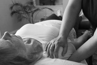 Hannah Currant giving Shiatsu to a client in supine, working on their shoulder