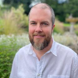 A headshot photo of Philip Lovemore with greenery behind him