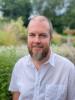 A headshot photo of Philip Lovemore with greenery behind him